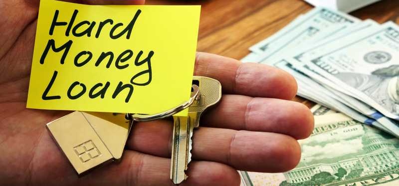 Hand holds houjse key and a note that says Hard Money Loan.
