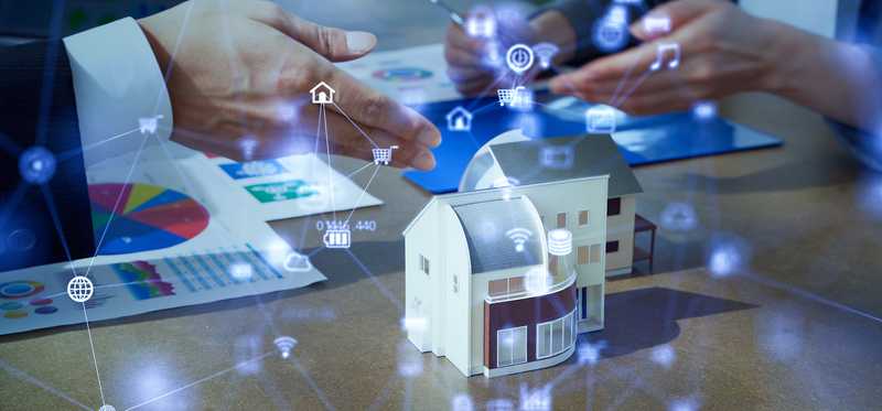 Image of model home on a desk with visual representation of smart home automations.