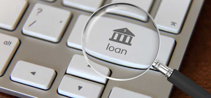 Computer keyboard with a magnifying glass hovering over a key that says loan.
