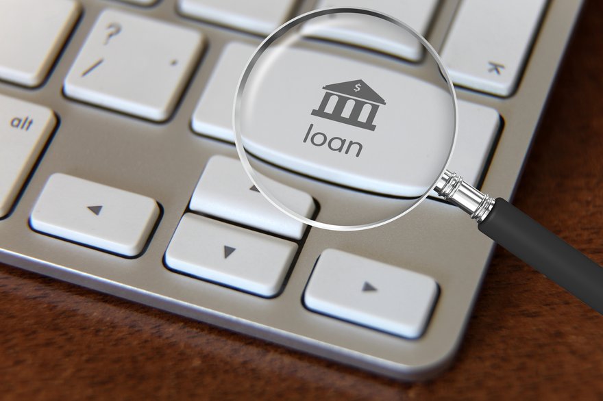 Computer keyboard with a magnifying glass hovering over a key that says loan.