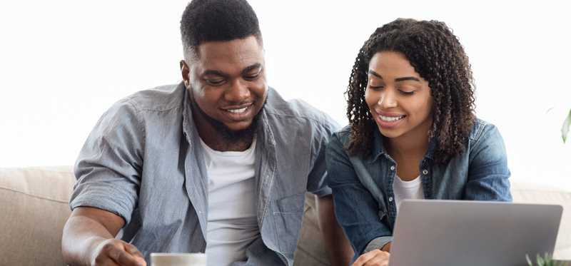 Two people smiling while looking at papers and laptop.