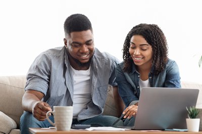 Two people smiling while looking at papers and laptop.