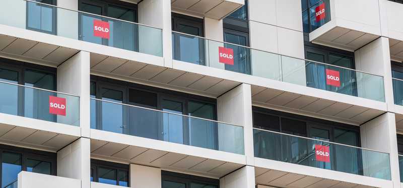Condo building with Sold signs on multiple balconies.