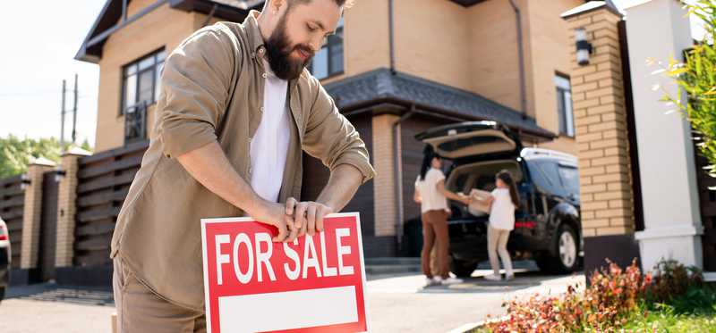 Person putting for sale sign in yard.