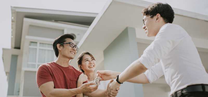 A real estate agent handing house keys to a happy couple.