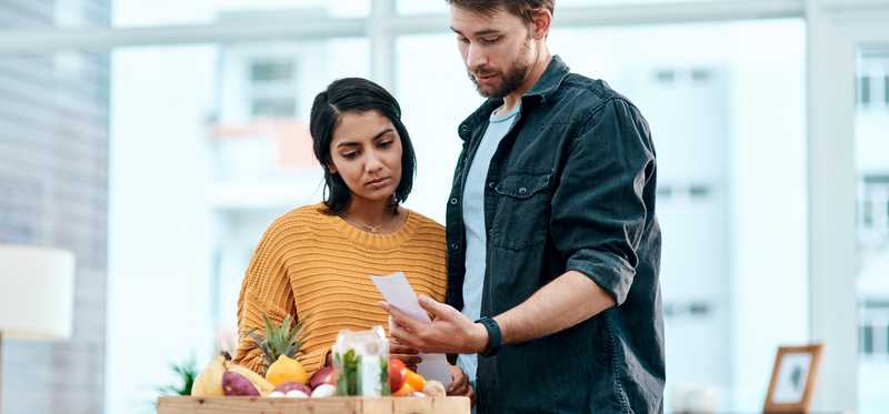 People looking surprised at receipt with food in box.