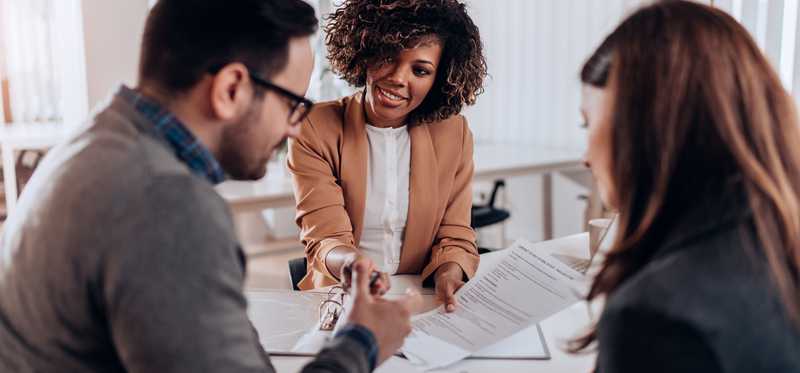 A realtor and two people signing a contract to buy a home.