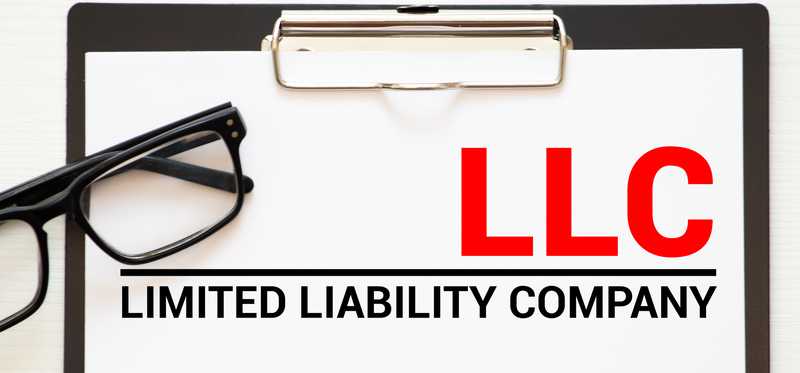 Clipboard with paper and glasses and the words Limited Liability Company, LLC.