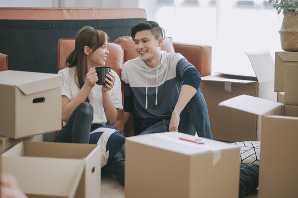 asia chinese couple sitting on floor resting after opening carton cardboard boxes in living room moving house