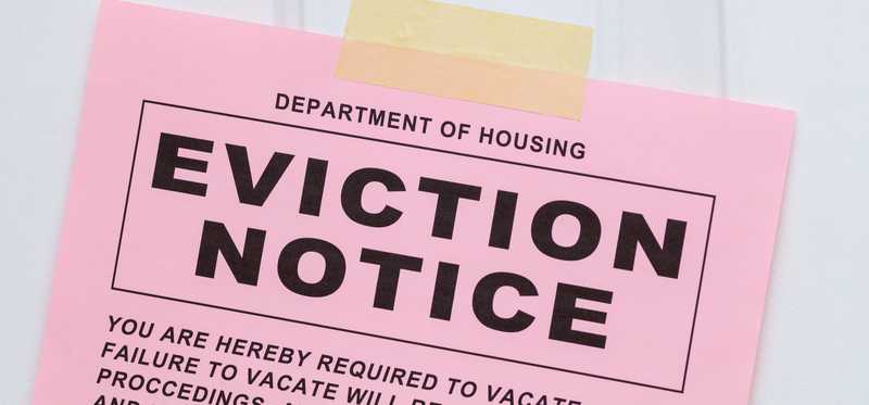 Pink eviction notice pinned on door.