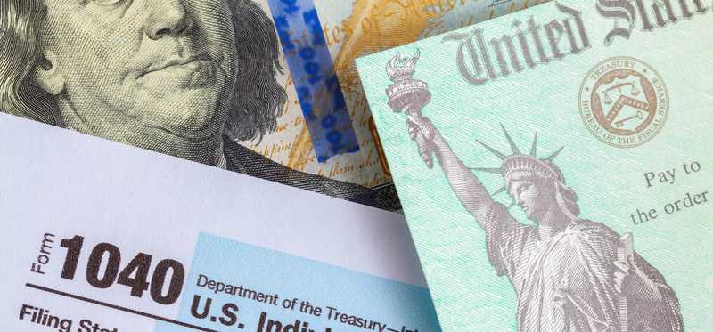 Picture of IRS Form 1040 with a tax refund check and a hundred dollar bill near it.