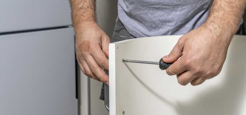 Person installing hardware on kitchen cabinet.