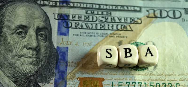 Letters SBA on blocks on top of money.