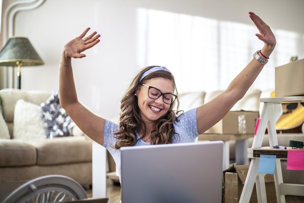 Person in front of computer is excited and smiling with hands in air.