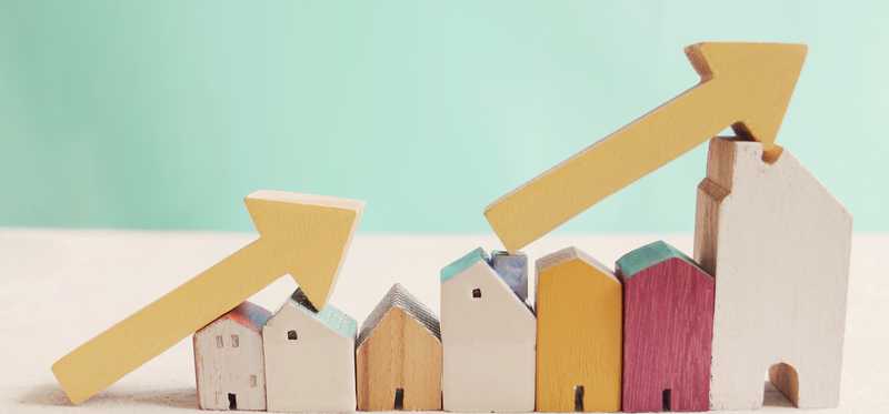 Toy houses stacked in a row with arrows pointing up at an incline.