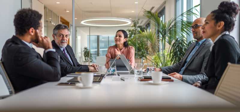 People sitting at a table and talking with one another in a boardroom.