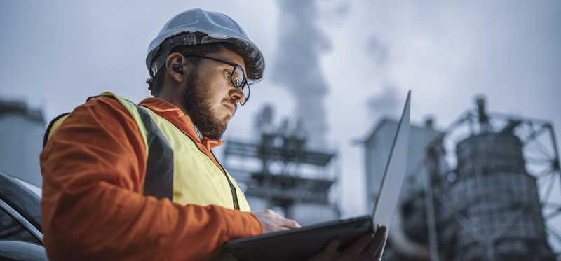 Person working on laptop in front of energy building.