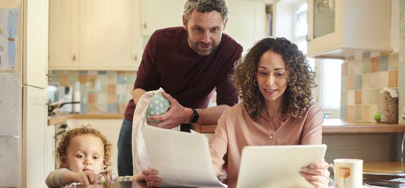 Family looking at paperwork at their kitchen table.