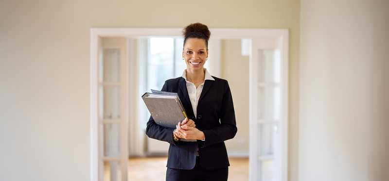 Real estate agent smiling inside of empty home.