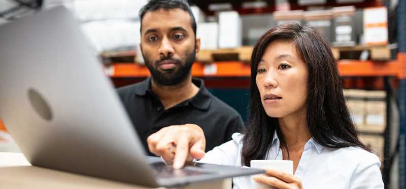 People looking at laptop in a warehouse.