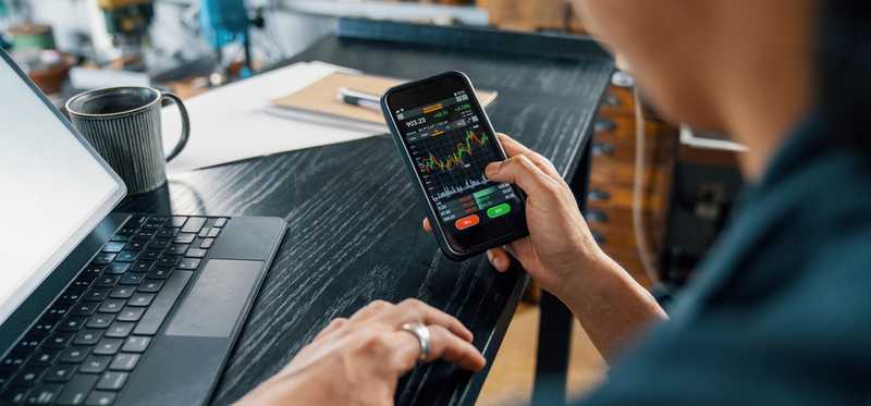 Person buying stocks on a cell phone.