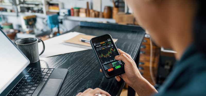 Person buying stocks on a cell phone.