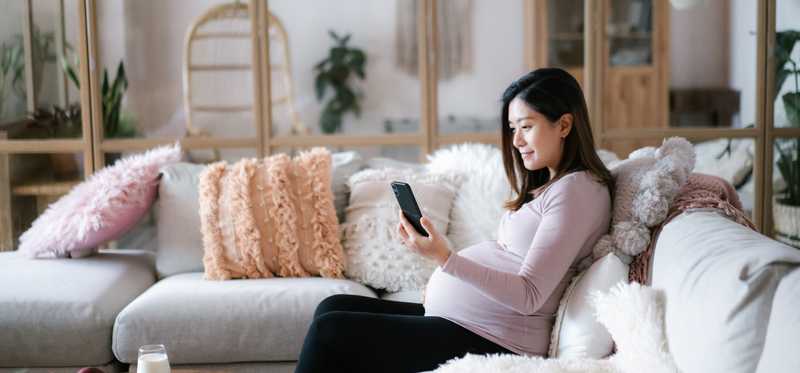 Person sitting on sofa and looking at phone.