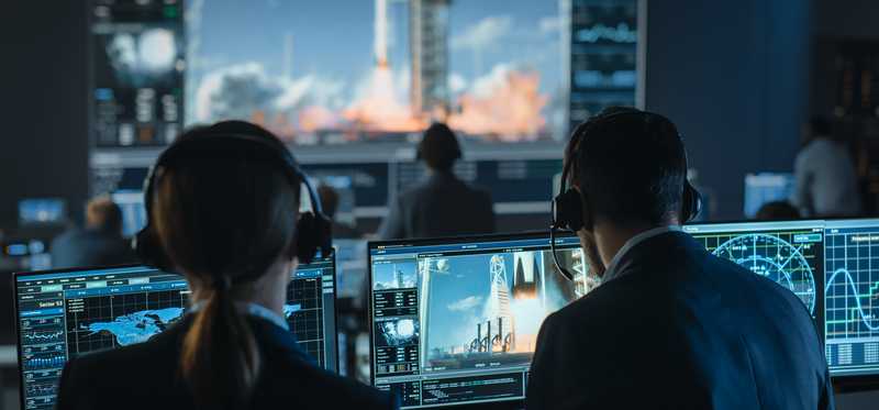 Group of people in mission control center witness successful space rocket launch.