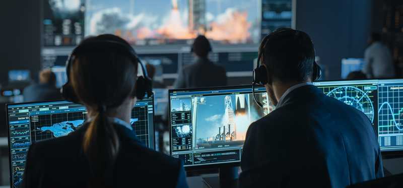 Group of people in mission control center witness successful space rocket launch.