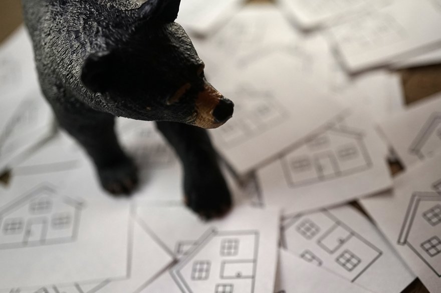 Bear figure on top of cards with houses stenciled on them.