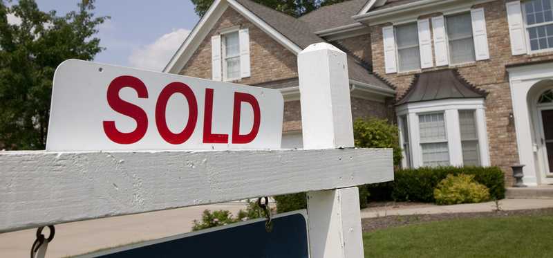 Sold sign in front of brick single-family home.
