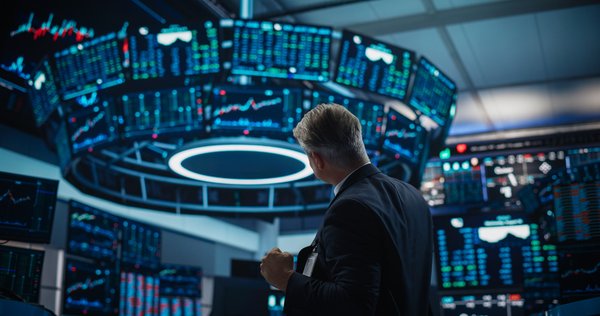A business person looking at stock charts on screens.