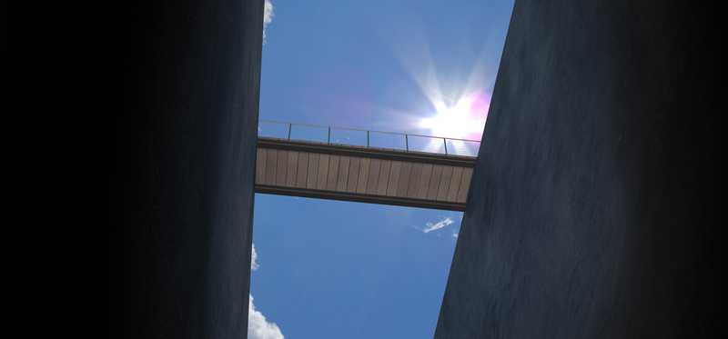 Bridge between two buildings with sky in background.