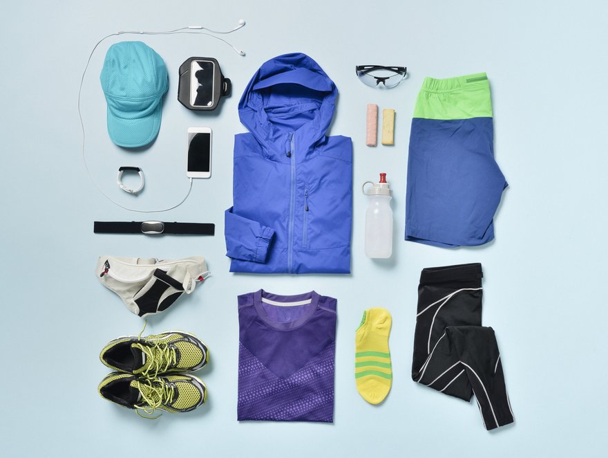 Jogging clothes and accessories organized on blue back.Items include: Smart Watch,smartphone