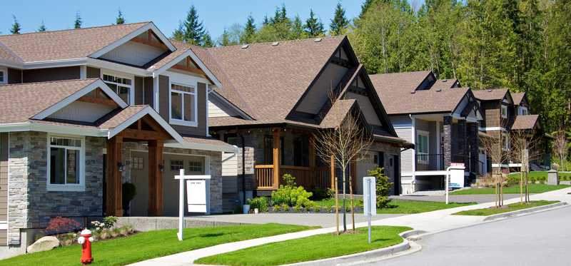 A block of homes with For Sale signs in two of the front yards