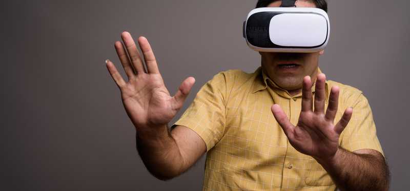 Person wearing virtual reality glasses and holding up their hands defensively.