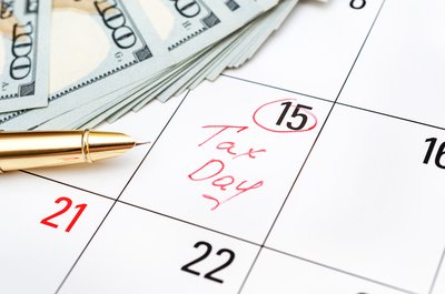 Tax Day written on the fifteenth day on a calendar with money and a pen beside it
