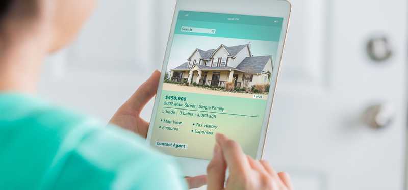 Person looking at a house listing on a tablet.