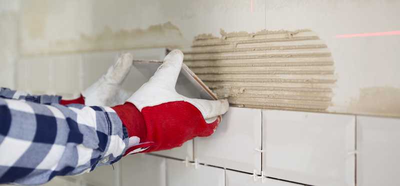 Person installing backsplash in kitchen.