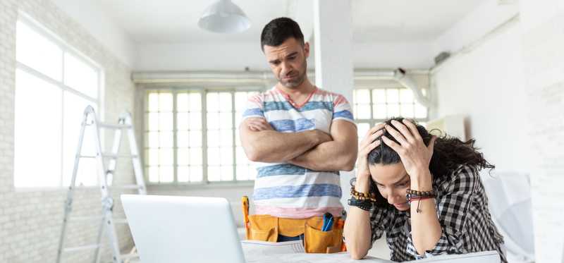 Two stressed out people looking over papers at a renovation site.