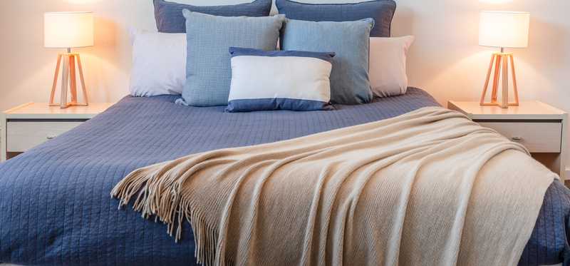 Staged bedroom with two side tables and blue pillows.
