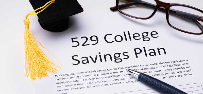 We see a little graduation cap, glasses and pen next to a paper that reads 529 college savings plan.