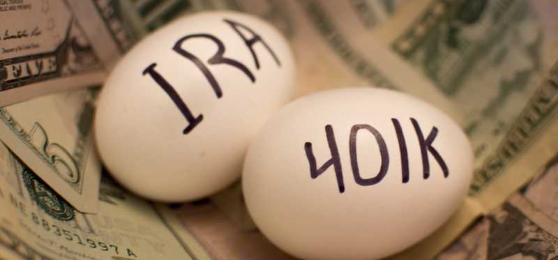 Two eggs sitting on a pile of cash, one labeled IRA and the other 401k.