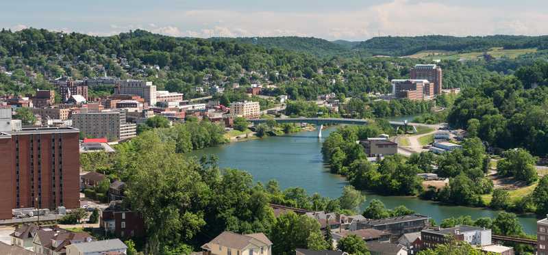Morgantown, West Virginia, with a river running through it and green hills in the background.