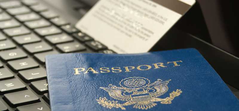 Passport and credit card sit on top of a laptop.