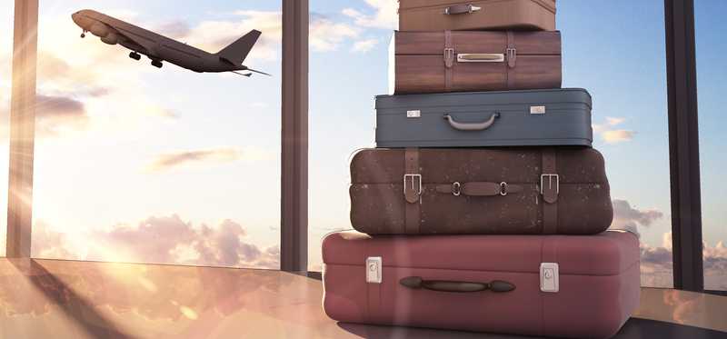 Stack of suitcases with a plane taking off in the background.