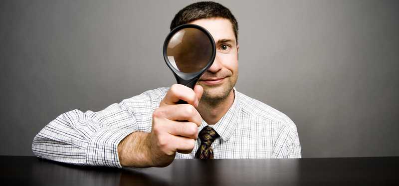 Person peering through magnifying glass.