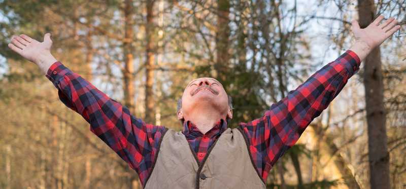 Person looking up in happiness with arms outstretched.