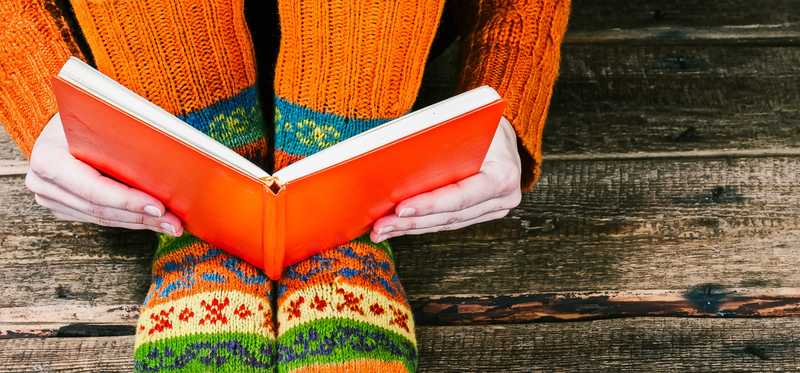 We see someone's feet in colorful socks next to an open book.