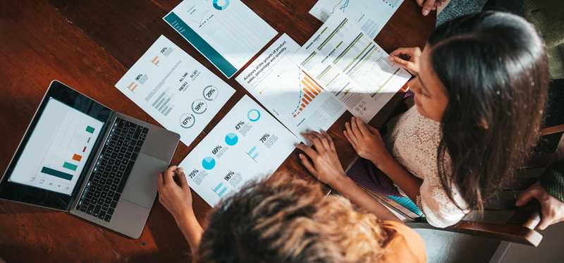 A group of folks is looking over business documents spread across a table.